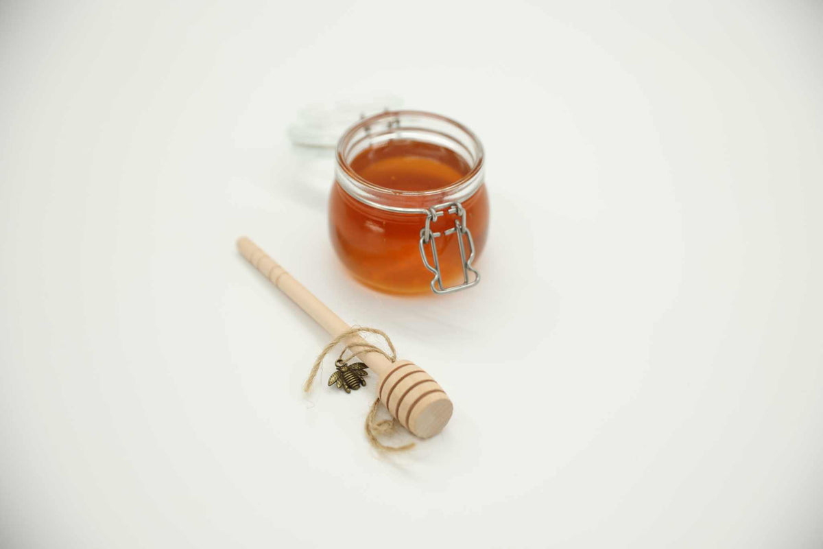 Honey dipper stick detail — natural uncoated wood spiral head for raw honey serving