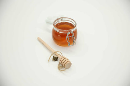 Honey dipper stick detail — natural uncoated wood spiral head for raw honey serving